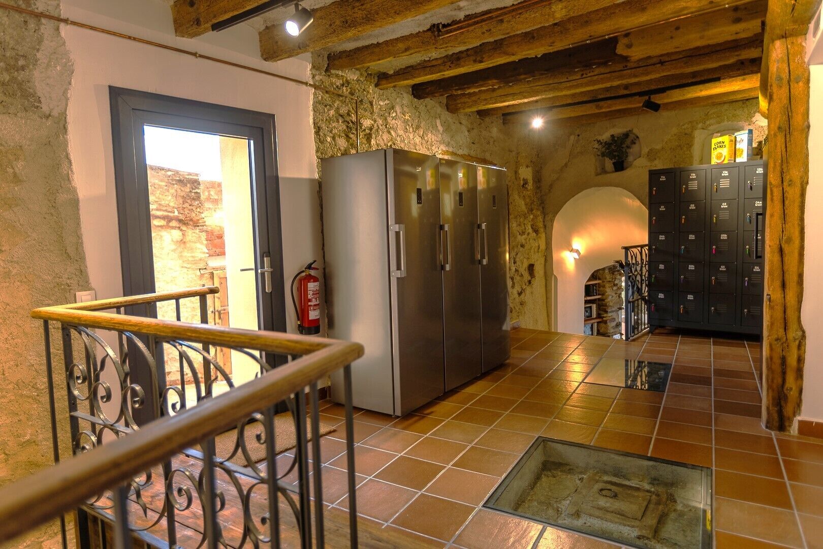 Un intérieur rustique avec un escalier, un réfrigérateur en acier inoxydable et une rangée de casiers.