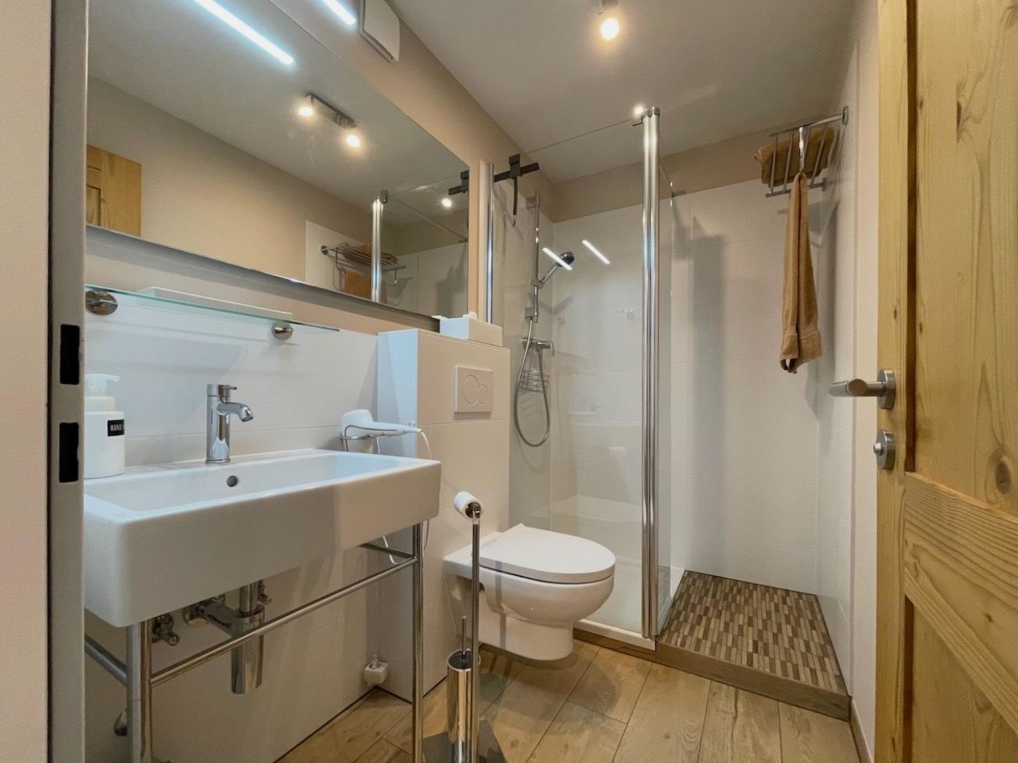 Une salle de bain moderne avec une douche à parois de verre, un lavabo blanc et des toilettes.
