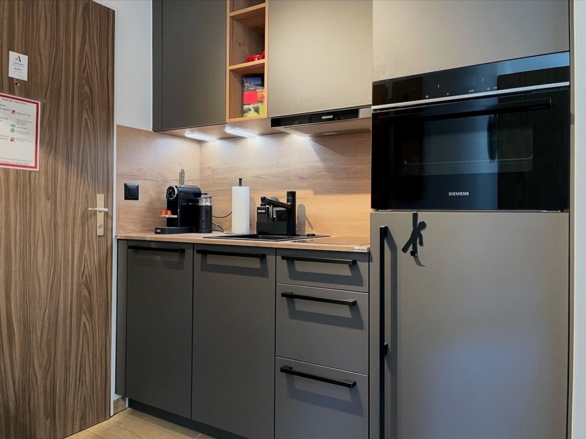 Eine moderne Küche mit einem Siemens-Kühlschrank, einer Kaffeemaschine und einer Holzarbeitsplatte.