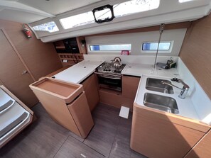 A compact galley with a stove, sink, and storage cabinets, featuring skylights and a view of the sky. - Sun-Kissed Sailing Adventure in the Sporades Islands from Volos, Thessaly (Volos)
