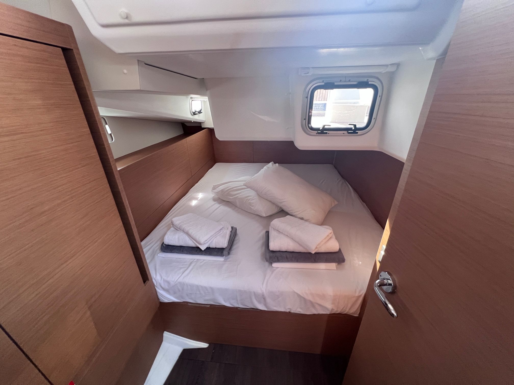 A compact cabin with a bed, a small window, and a storage cabinet.