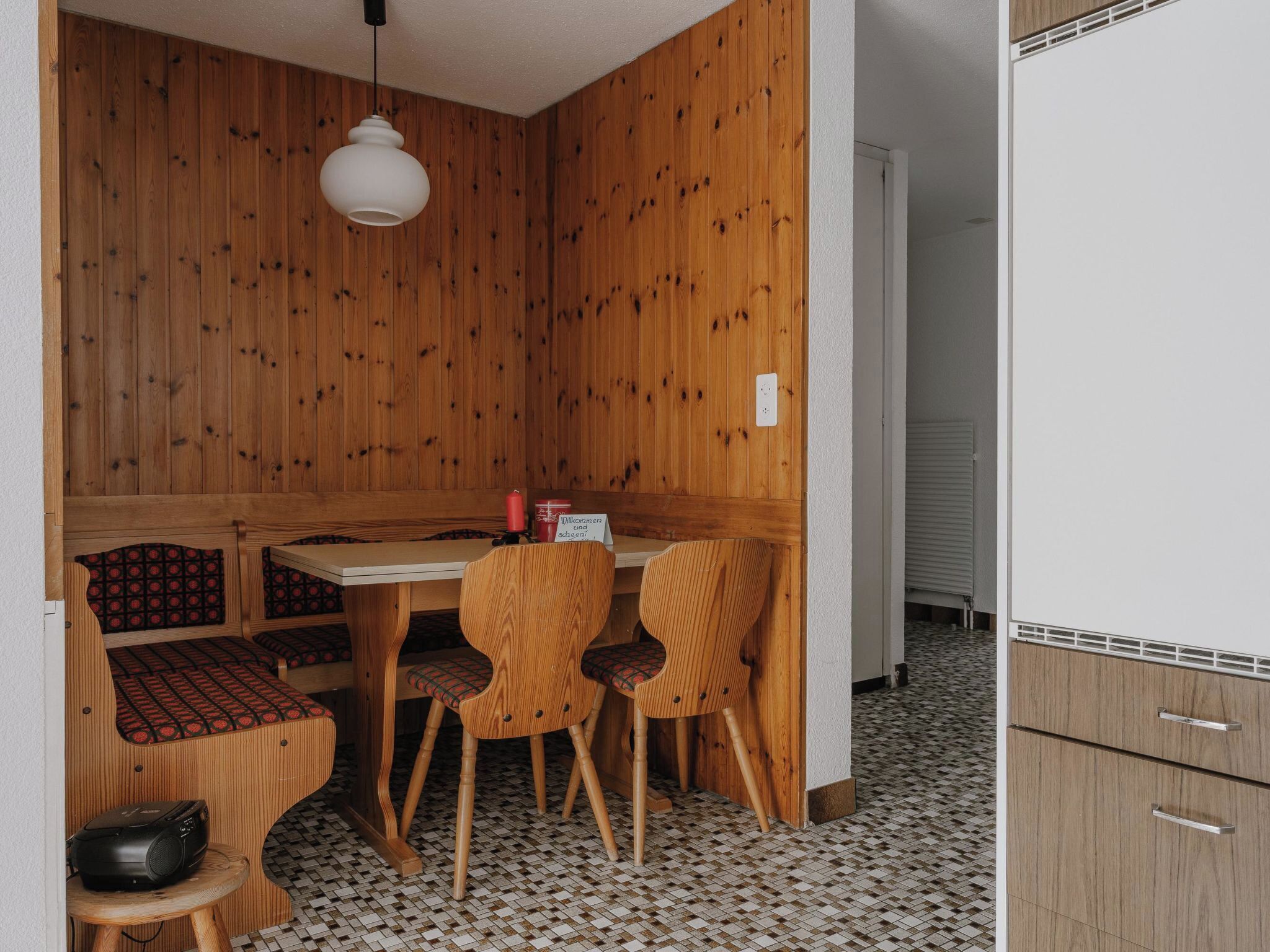 Un coin repas compact avec une table et des chaises en bois, un petit tabouret et un banc à motifs.
