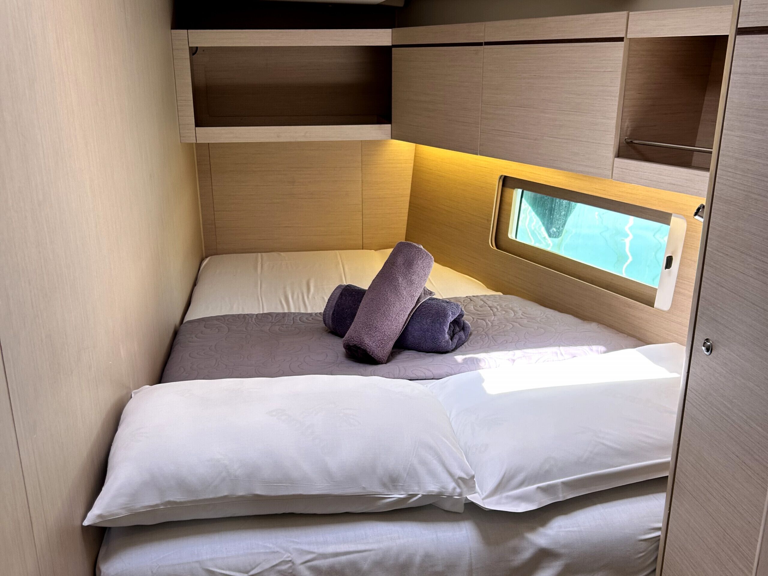 Una cama compacta con ventana, una toalla y cabecera.