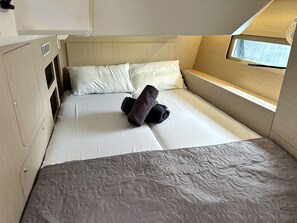 Ein kleines, helles Schlafzimmer mit Bett, Kissen und einem Fenster.