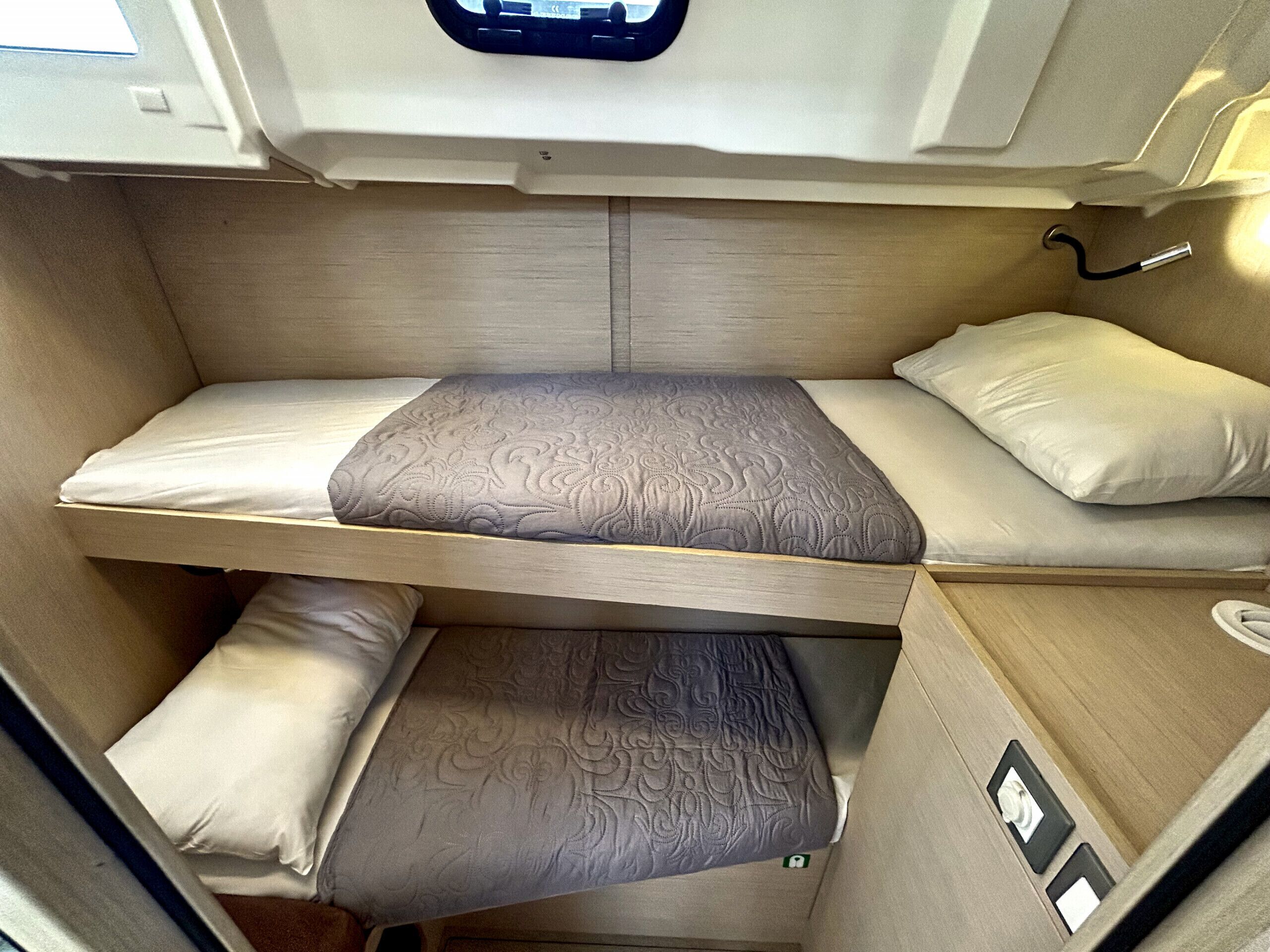 A compact RV interior with a bunk bed, a small table, and a window.