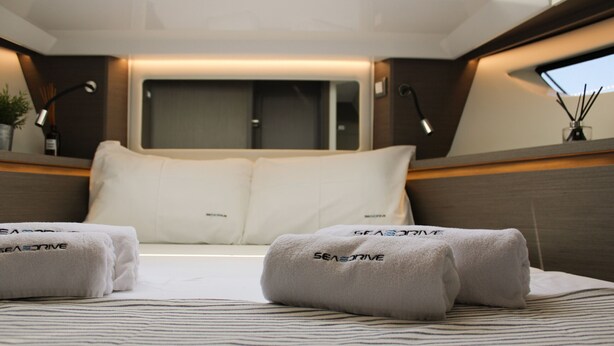 A neatly made bed with white linens and pillows, a window with curtains, and a bedside table with a lamp and a small vase with reeds. - Sun-Kissed Sailing Adventure in Zadar, Croatia (Zadar)