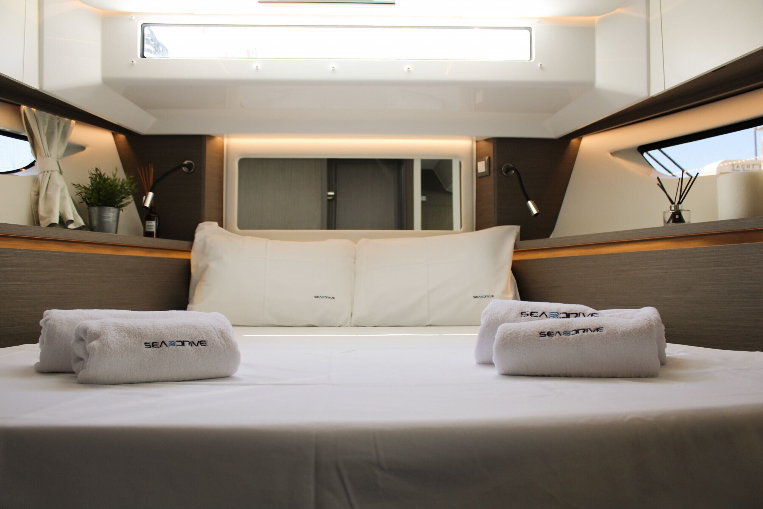 Un dormitorio con cama, almohadas y dos toallas con la marca 'SEASIDE'.