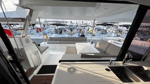 El interior de un barco con zona de comedor, lavamanos y vistas a otros barcos.