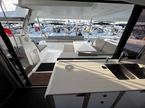Schiffsinnenraum mit Essbereich, Spüle und Blick auf andere Boote.