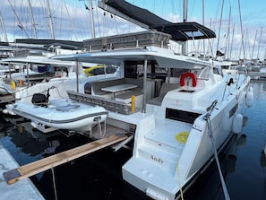 Un port de plaisance où sont amarrés de nombreux bateaux, avec un espace de repos abrité et le nom « Andy » écrit sur le côté d’un bateau.