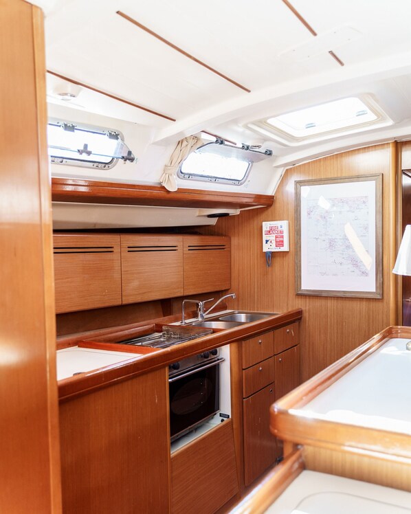 A compact galley kitchen with a stove, sink, and overhead storage.