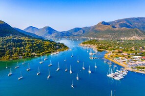 A marina with numerous sailboats docked, surrounded by lush green hills and mountains.