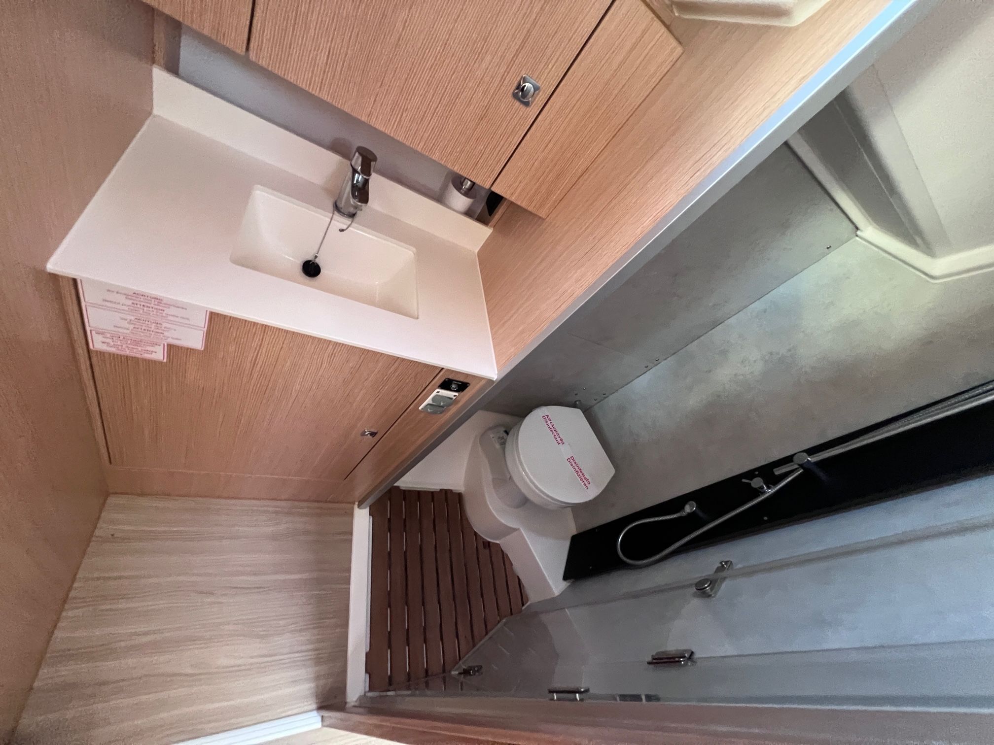 A compact bathroom with a white sink, wooden cabinets, and a toilet.
