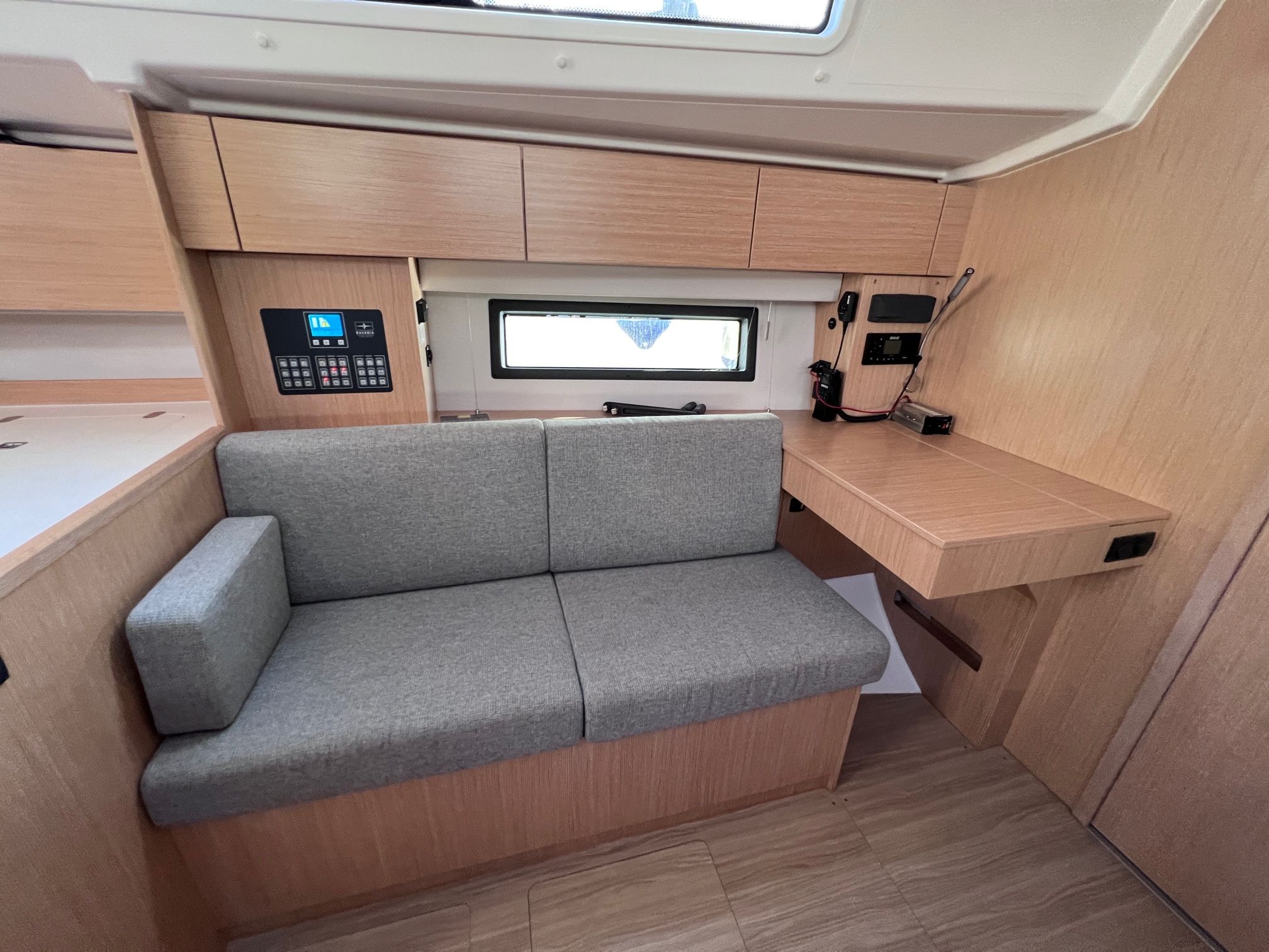 Eine kleine Küchenzeile mit grauem Sofa, Holzschränken und einer kompakten Arbeitsfläche.