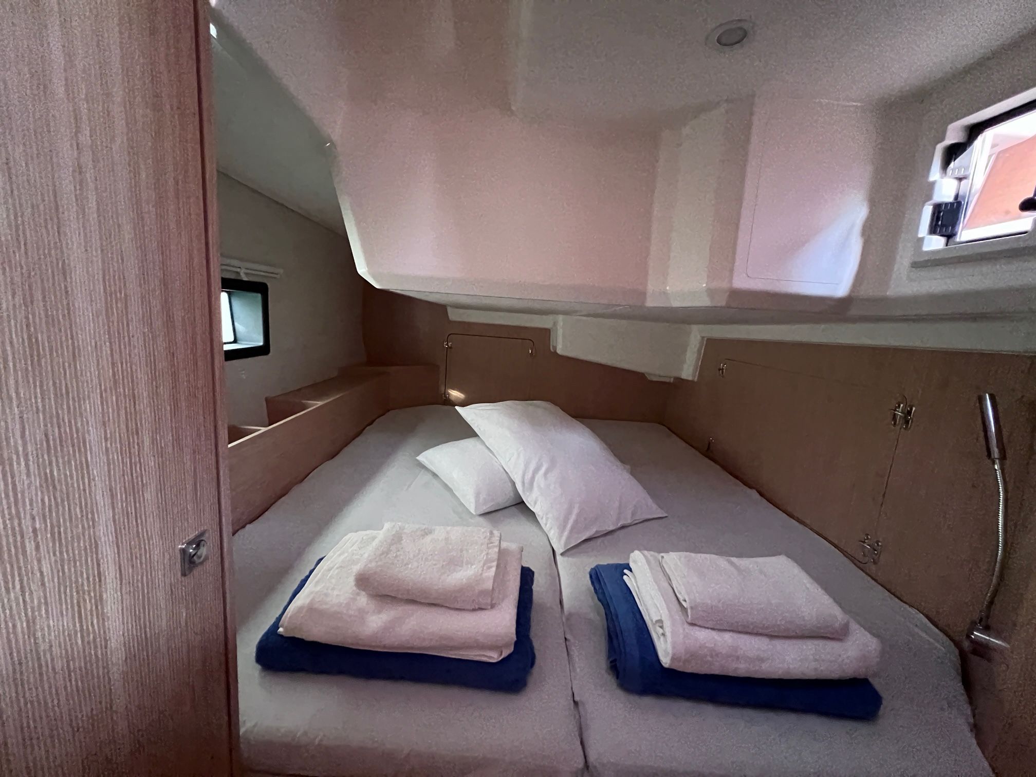 A compact, single-bed room with a bunk bed above, a small window, and a shower area.