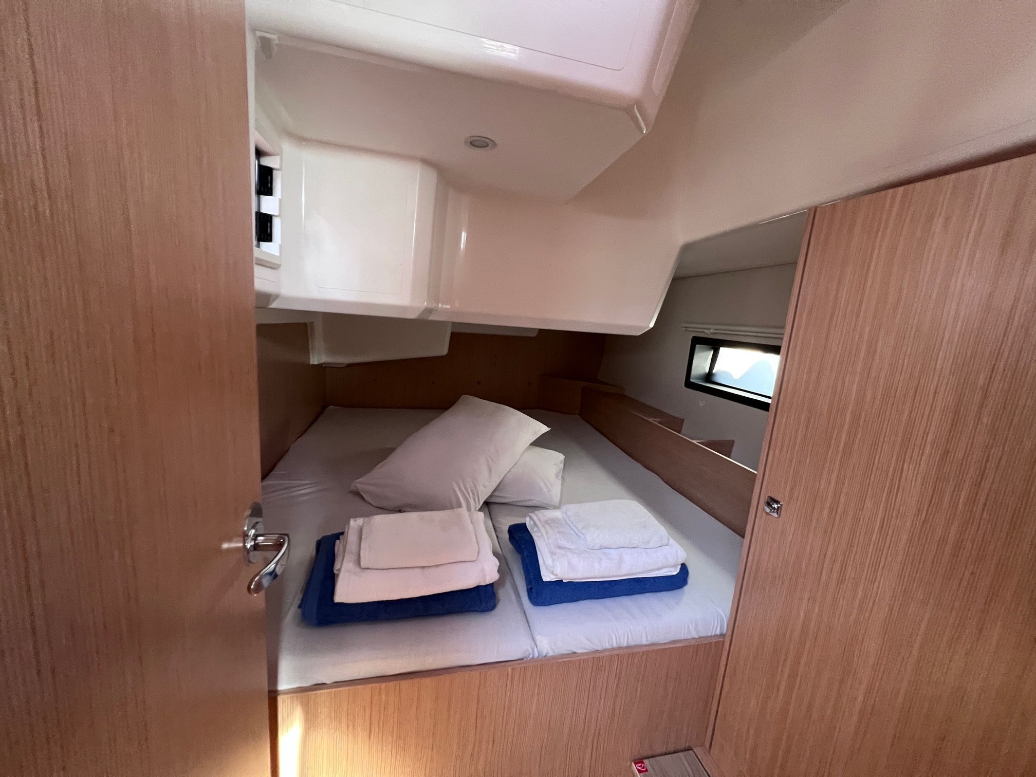 Una cabina compatta con un letto a castello, un piccolo oblò e un armadietto bianco.