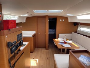 A compact galley with a stove, a small refrigerator, and a sink. There is a dining area with a table and benches.