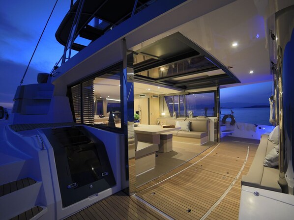 A modern yacht interior with a dining area, seating, and a view of the sea.