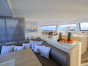 A modern kitchen with a central island, a dining area with a sofa, and large windows with ocean views.