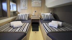 A compact room with two beds, a small table, and a bench. - Sun-Kissed Sailing Adventure in Islas Sarónicas (Alimos)