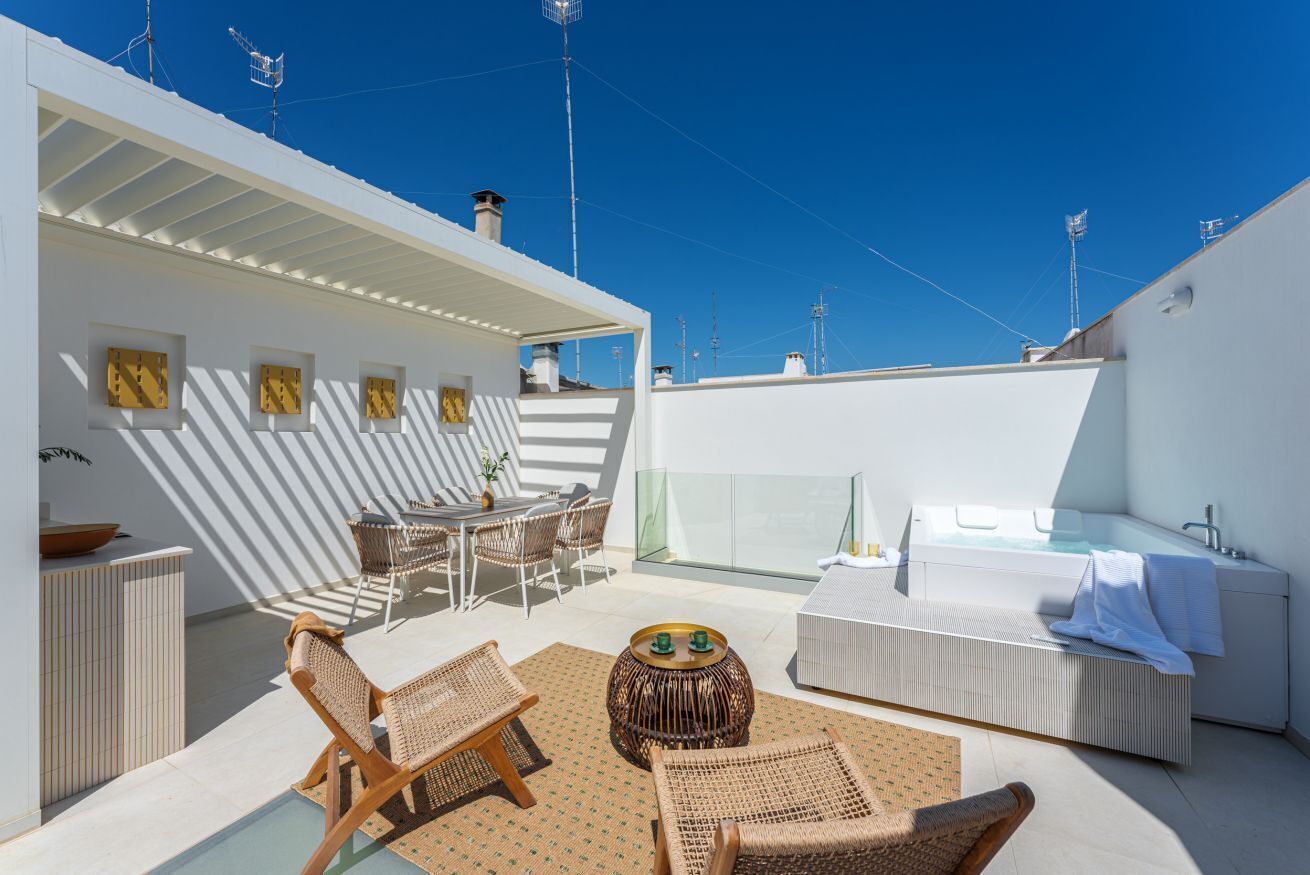 Une terrasse sur le toit aménagée avec un espace salon, un jacuzzi et un coin repas.