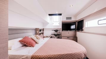Ein modernes Schlafzimmer mit Bett, Nachttischen, einem Fernseher und einem Fenster.