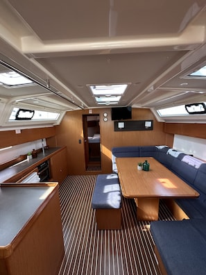 A compact galley with a wooden countertop, a bench, and a table with cushions. - Sun-Kissed Sailing Adventure in Zadar, Croatia (Drage)