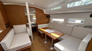 A compact interior with a dining area, seating, and a small kitchenette. - Dubrovnik Delight: A Sun-Kissed Sailing Experience (Komolac)