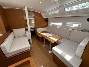 A compact interior with a dining area, seating, and a small kitchenette. - Dubrovnik Delight: A Sun-Kissed Sailing Experience (Komolac)
