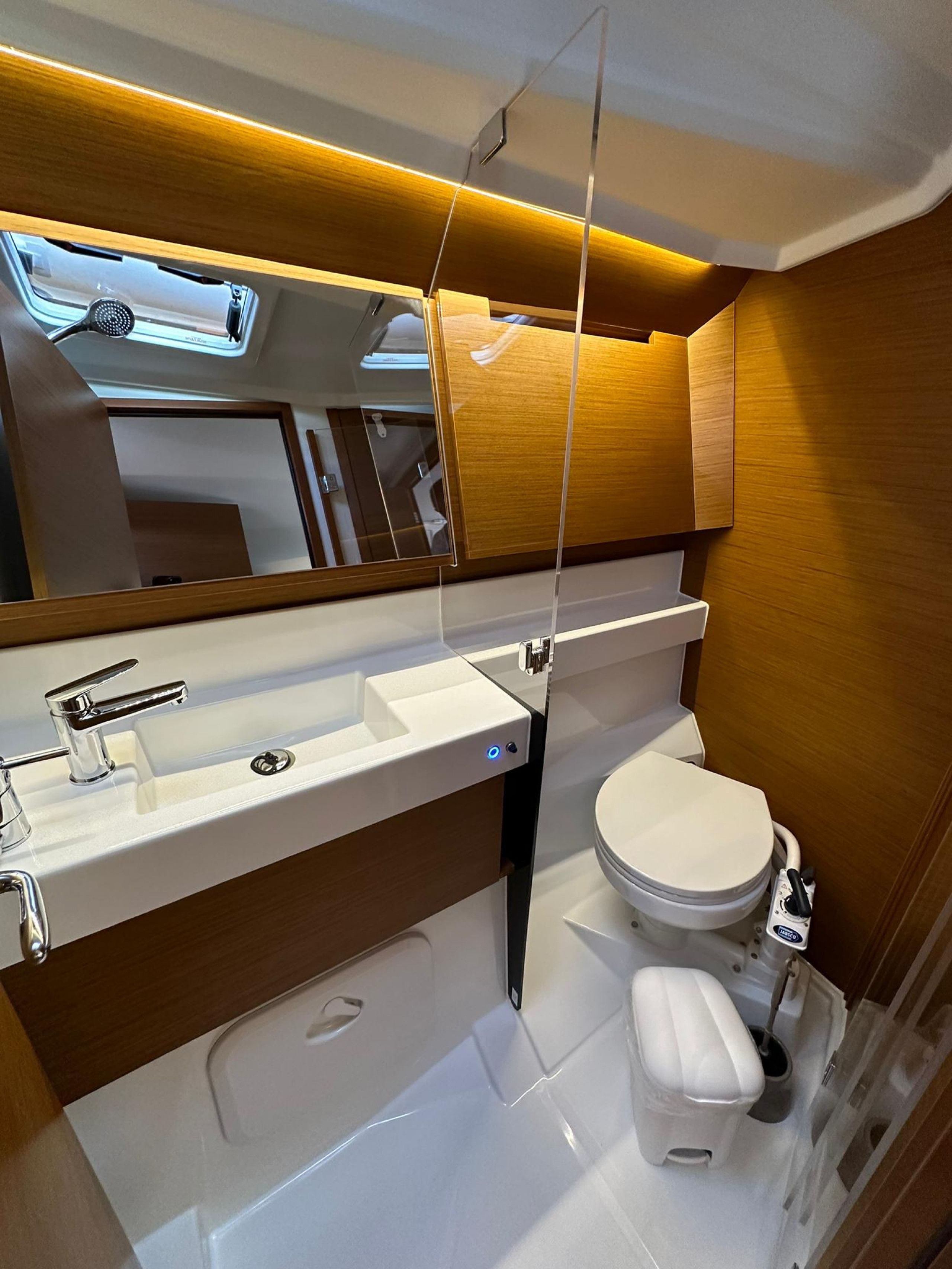Un baño pequeño con lavamanos, espejo y retrete blancos.