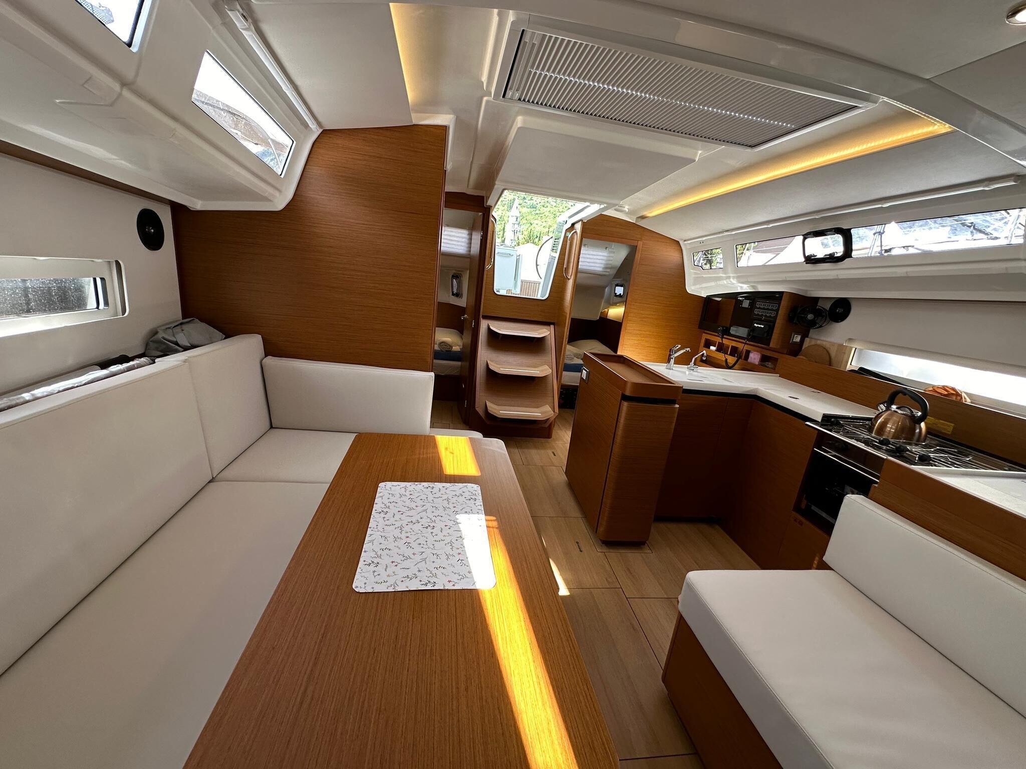 Un intérieur de bateau compact comprenant un coin salon, une petite kitchenette et une fenêtre laissant entrer la lumière naturelle.