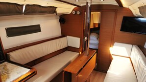 A compact interior with a bed, a small table, and a bench. - Sun-Kissed Sailing Adventure in Zadar, Croatia (Drage)