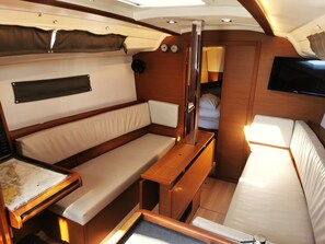 Un espacio interior pequeño con una cama, una mesita y un banco.
