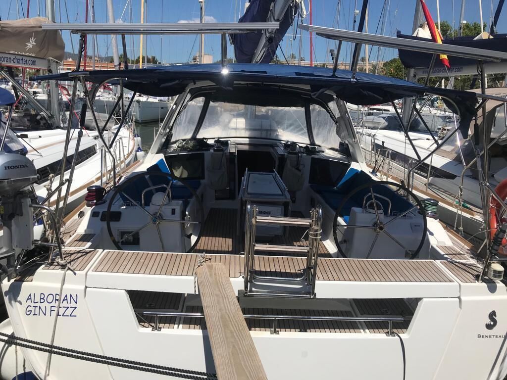 A sailboat with a covered cockpit, a steering wheel, and a name 'ALBORAN GIN FIZZ' on the side.