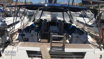 A sailboat with a covered cockpit, a steering wheel, and a name 'ALBORAN GIN FIZZ' on the side.