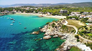 A coastal town with clear turquoise waters, rocky outcrops, and a beach area.