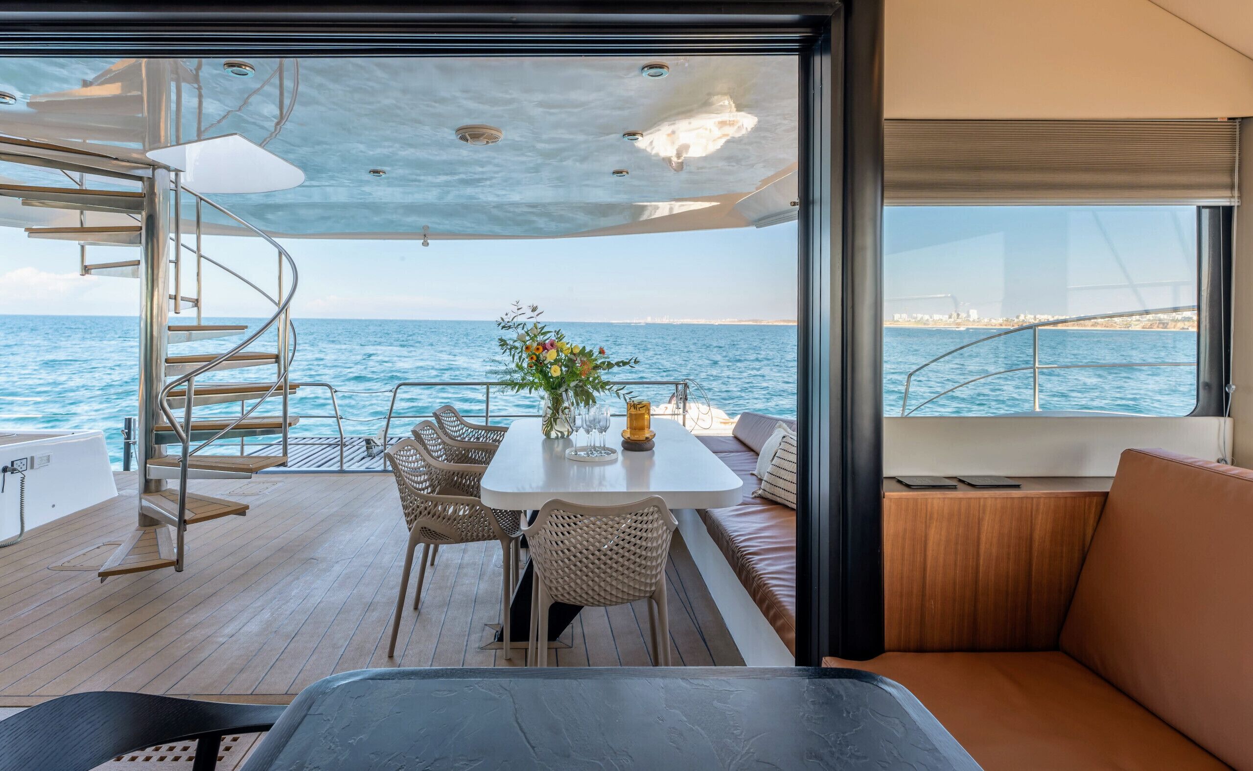 Um terraço com mesa, cadeiras e um sofá, com vista para o mar.