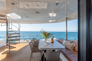 A yacht deck with a table, chairs, and a sofa, overlooking the sea. - Sun-Kissed Sailing Adventure in the Saronic Islands (Lavrio)