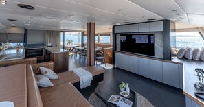 A modern interior with a sofa, dining area, kitchen, and a large TV screen. - Sun-Kissed Sailing Adventure in the Saronic Islands (Lavrio)