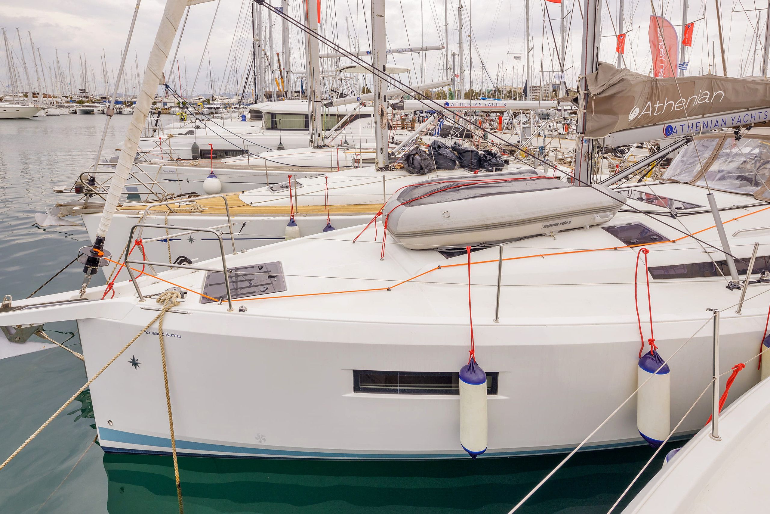 A marina with multiple yachts docked, including a white yacht with a blue stripe and a cabin.
