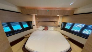 Ein Bett mit Kopfteil, zwei Fenster mit Jalousien und eine Decke mit Einbaustrahlern.