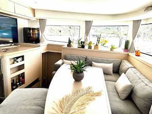 A modern interior with a sofa, a small table with a plant, a TV, and a window with curtains.