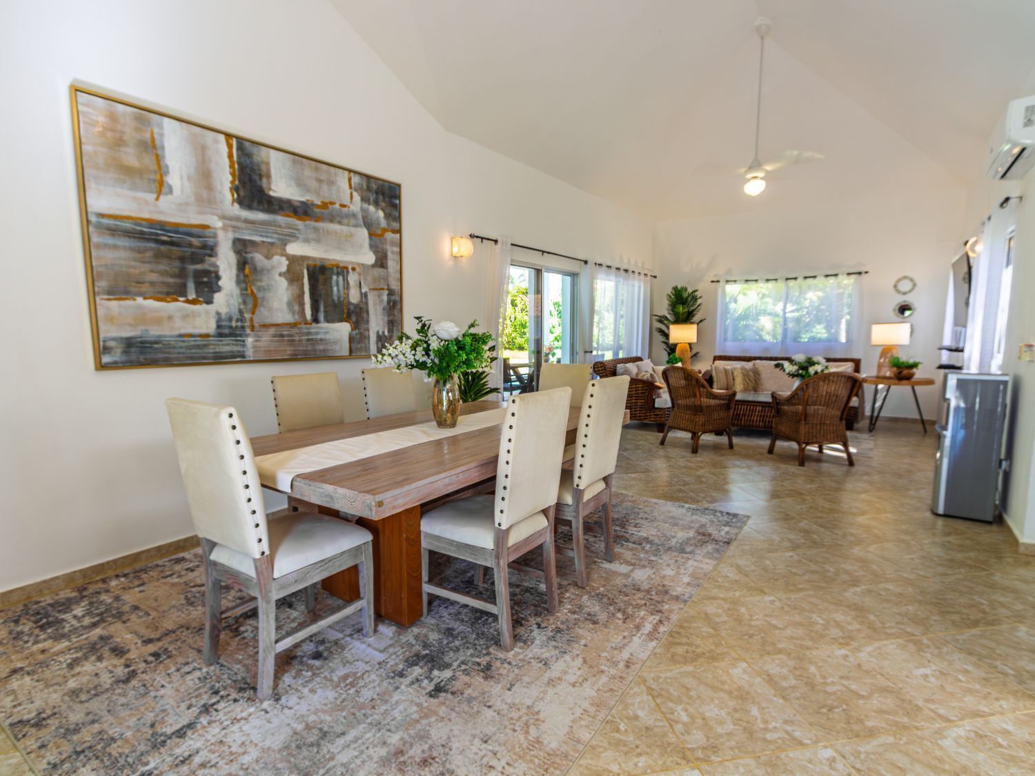 A spacious dining area with a long wooden table, several chairs, and a large abstract painting on the wall.