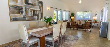 A spacious dining area with a long wooden table, several chairs, and a large abstract painting on the wall.