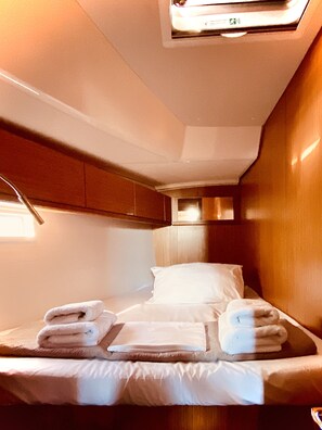 A compact, well-lit room with a bed, pillows, and neatly folded towels. - Sun-Kissed Sailing Adventure in the Ionian Islands, Lefkada (Lefkada)