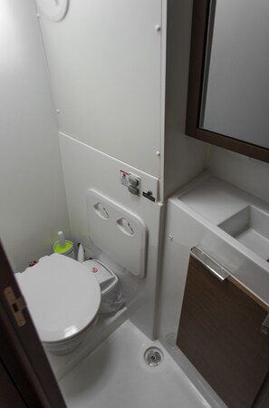 A compact bathroom with a toilet, bidet, and a small sink. - Sun-Kissed Sailing Adventure in Islas Sarónicas (Alimos)