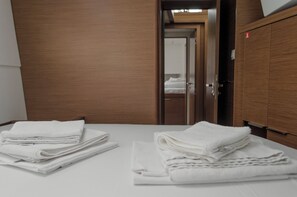 A hotel room with a neatly made bed, a wooden wardrobe, and a door leading to another room. - Sun-Kissed Sailing Adventure in Islas Sarónicas (Alimos)