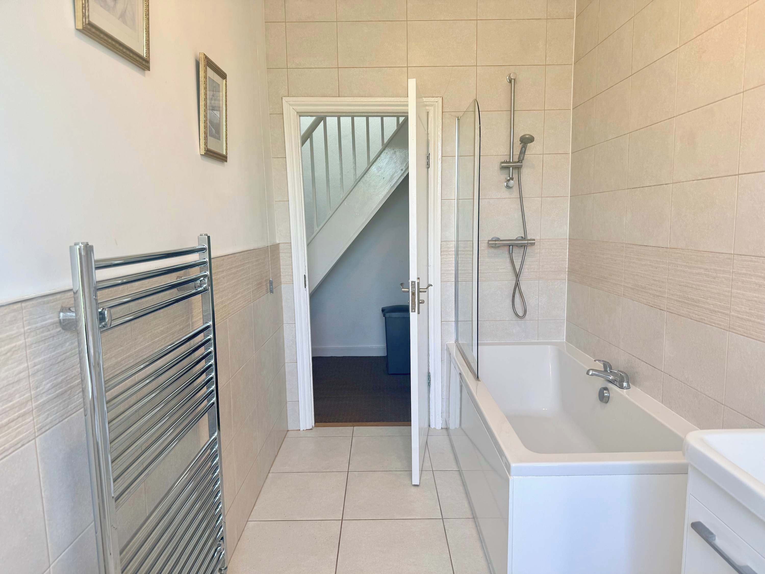 A bathroom with a bathtub, shower, and a towel rack.