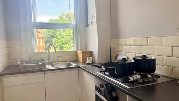 Una cocina con ventana, pileta, estufa y alacenas.