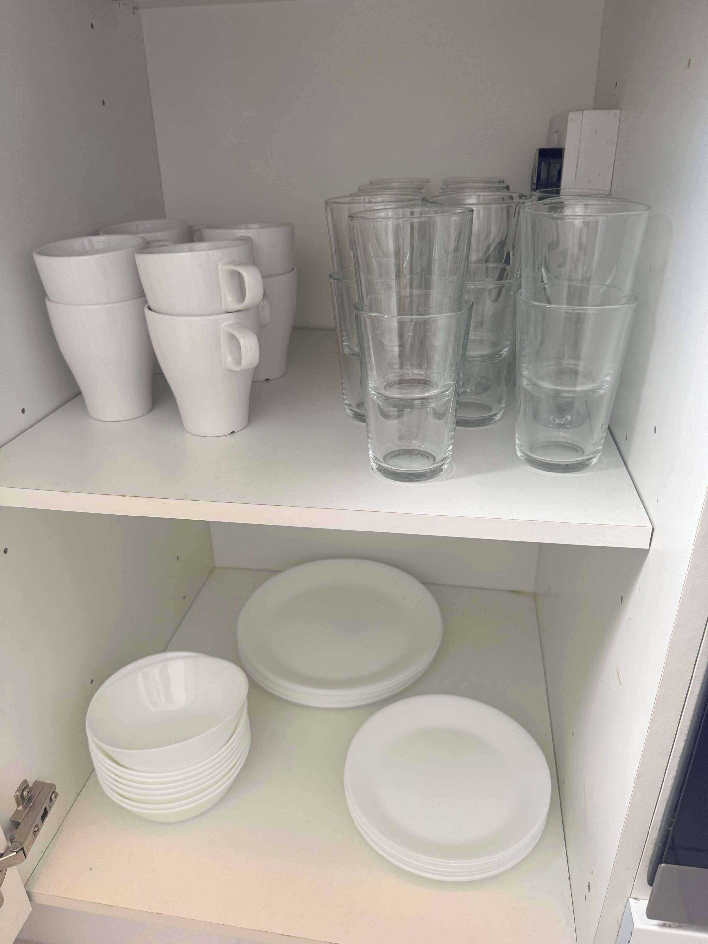 Un espacio de almacenamiento con vasos, tazas y platos blancos.
